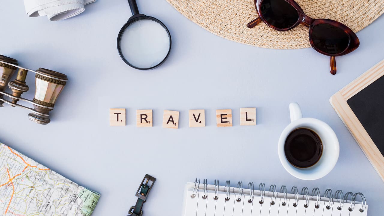 A table filled with many things which include travel letters, sunglasses, a cup of coffee and a notepad