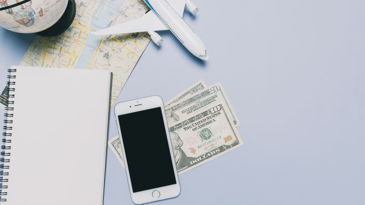 Money and smartphone on a table with some travelling stuff