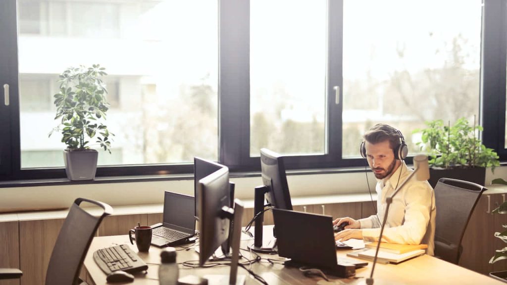 man-part-of-company-uniform-program-with-headphones-facing-monitor