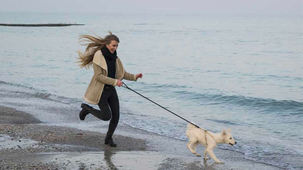woman playing with her dog at the seaside
