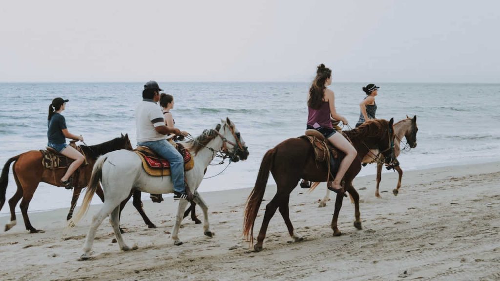 people riding horses on beach