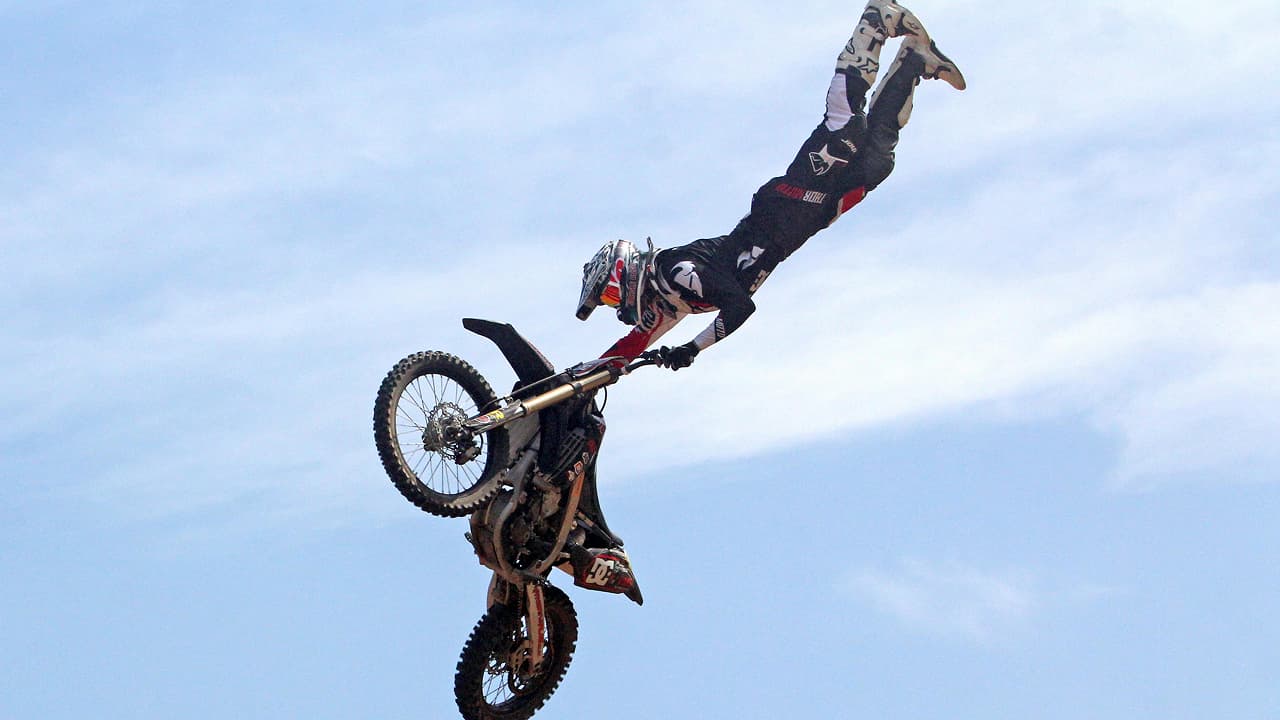 A person holding motorcycle under blue sky