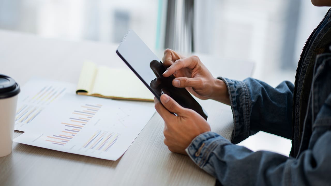 A side view of an employee using a tablet to view fintech apps