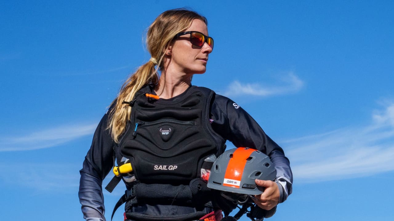 Hannah Mills is standing while holding a helmet