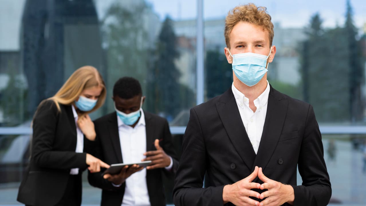 A front view of three people wearing masks and standing