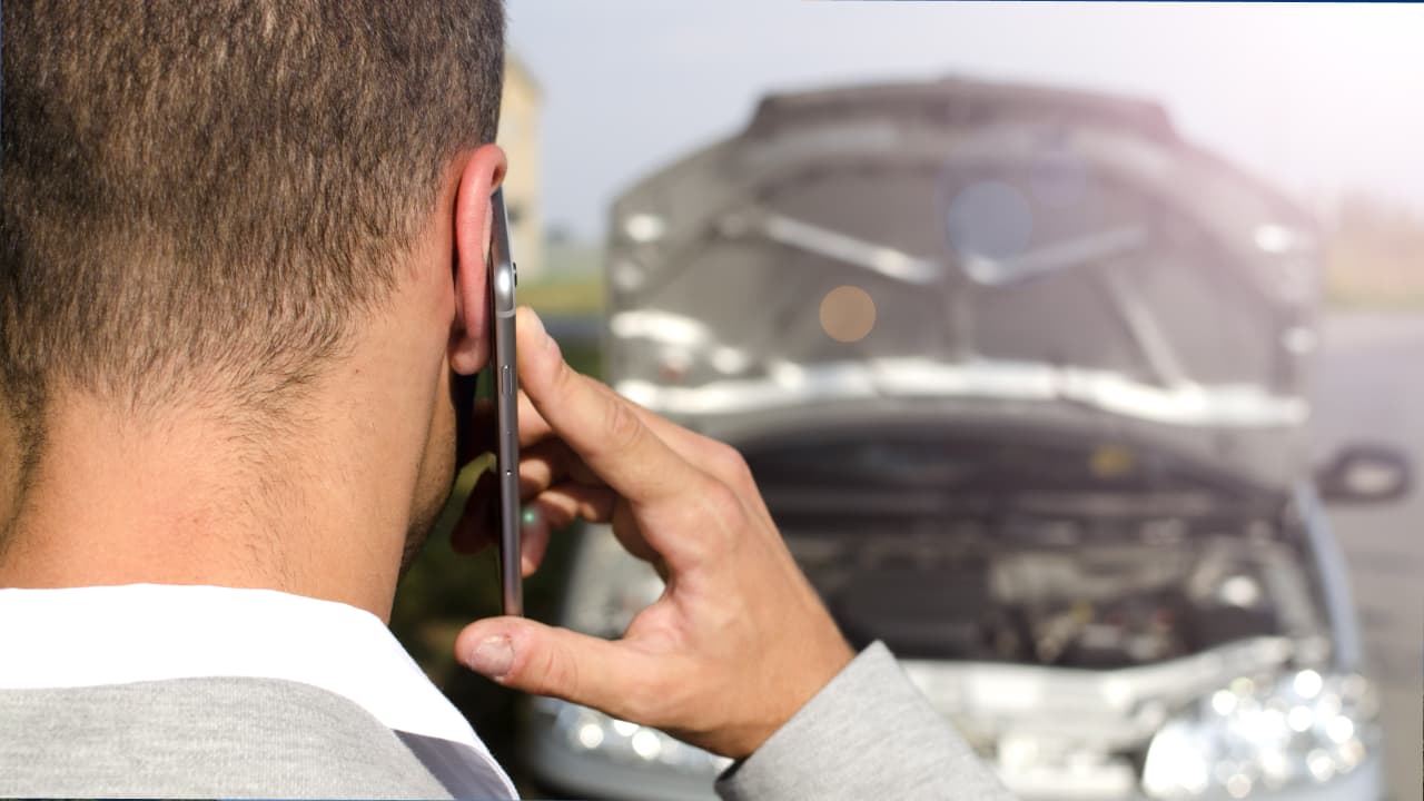 man standing by broken vehicle near car accident scene and calling