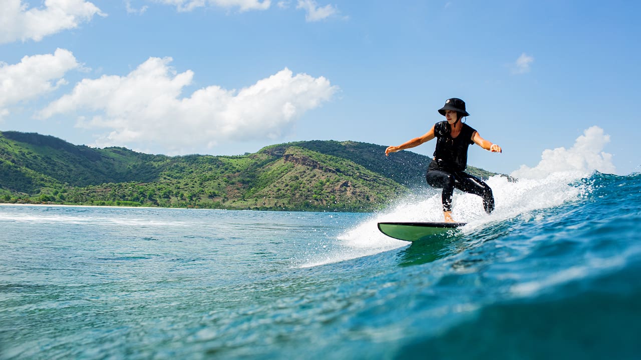 A surfer riding on a blue wave