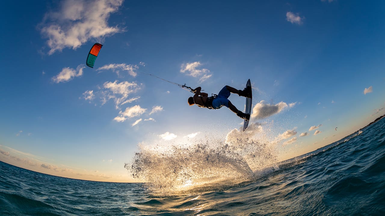 Person surfing and flying a parachute at the same time