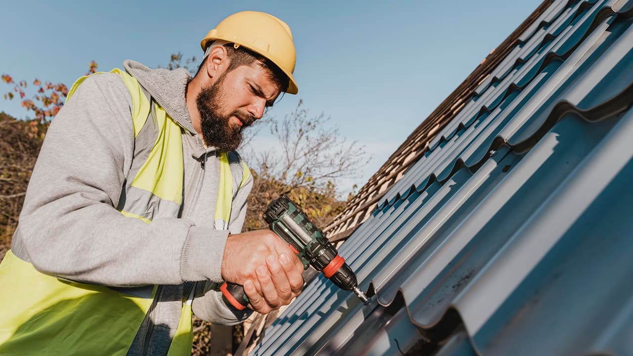 A man is working on a roof with a drill to prepare a summer rental home
