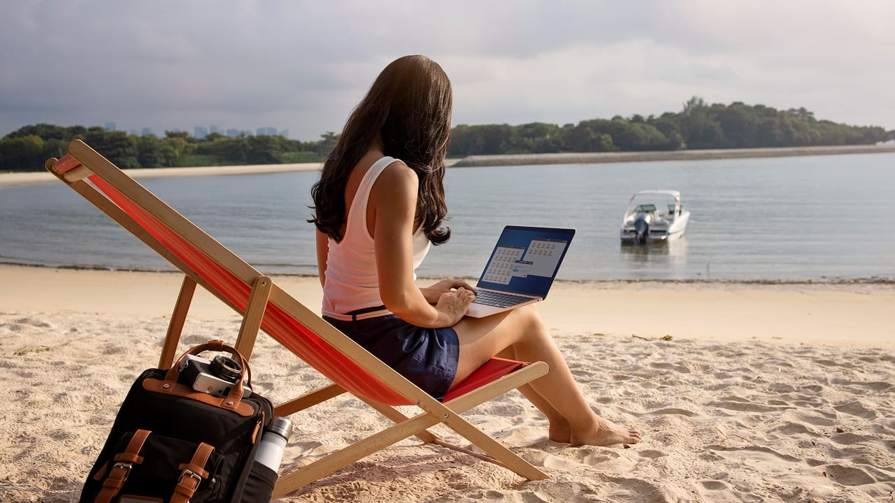 A digital nomad women working on a laptop at a lakeside