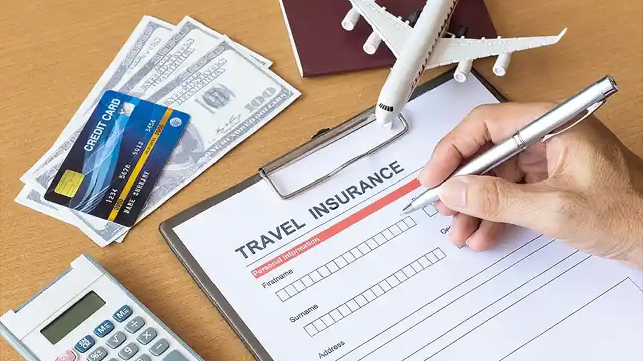 A hand is holding a pen while completing a travel insurance form.