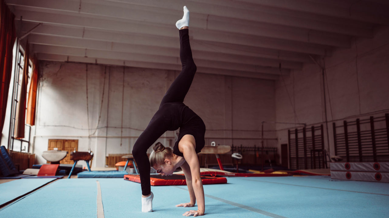 A blonde hair women performing some stunt in gymnastics