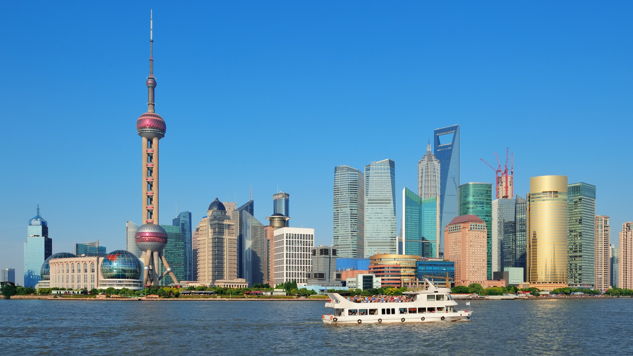 Many buildings behind the sea and a ship sailing
