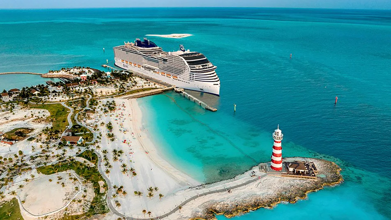 MSC world america cruise ship docked beside a tropical island