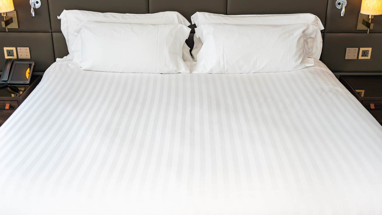 View of a bed with white pillows highlighting a supportive mattress topper for back pain