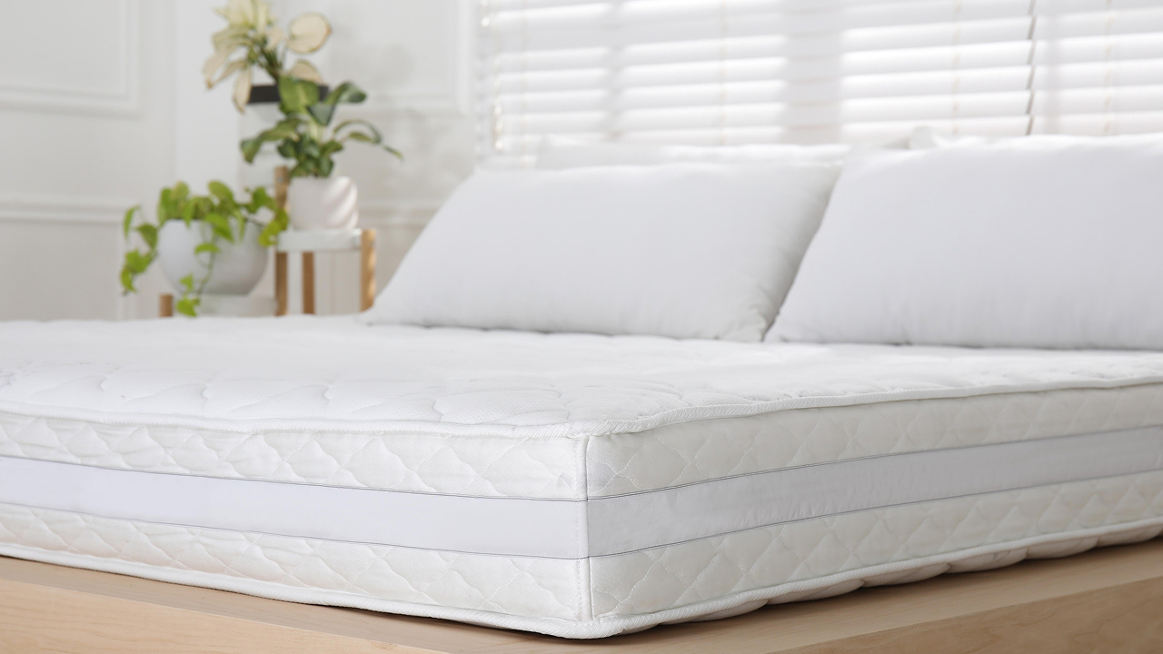 A bed with a white mattress topper
