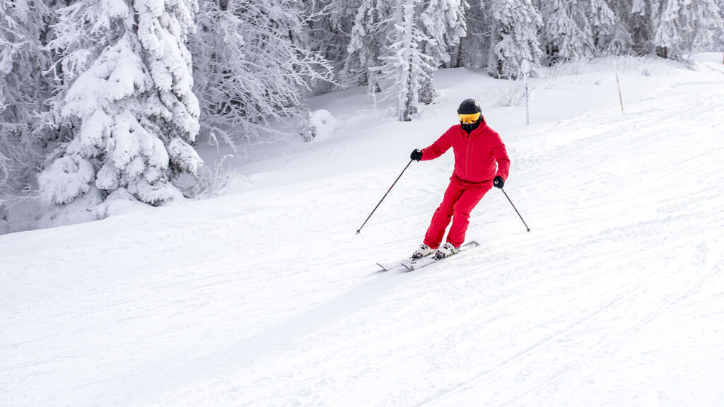 A man wearing red clothes is skiing