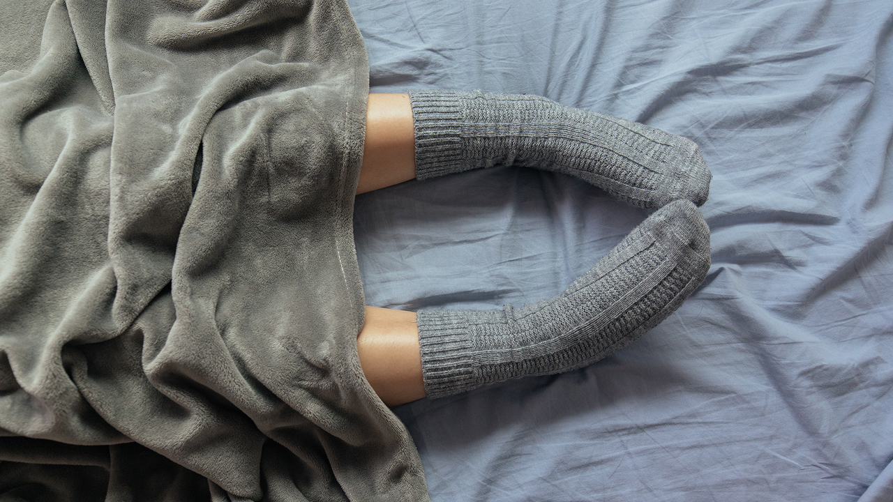 Top view of a person’s feet resting on a blue bedsheet