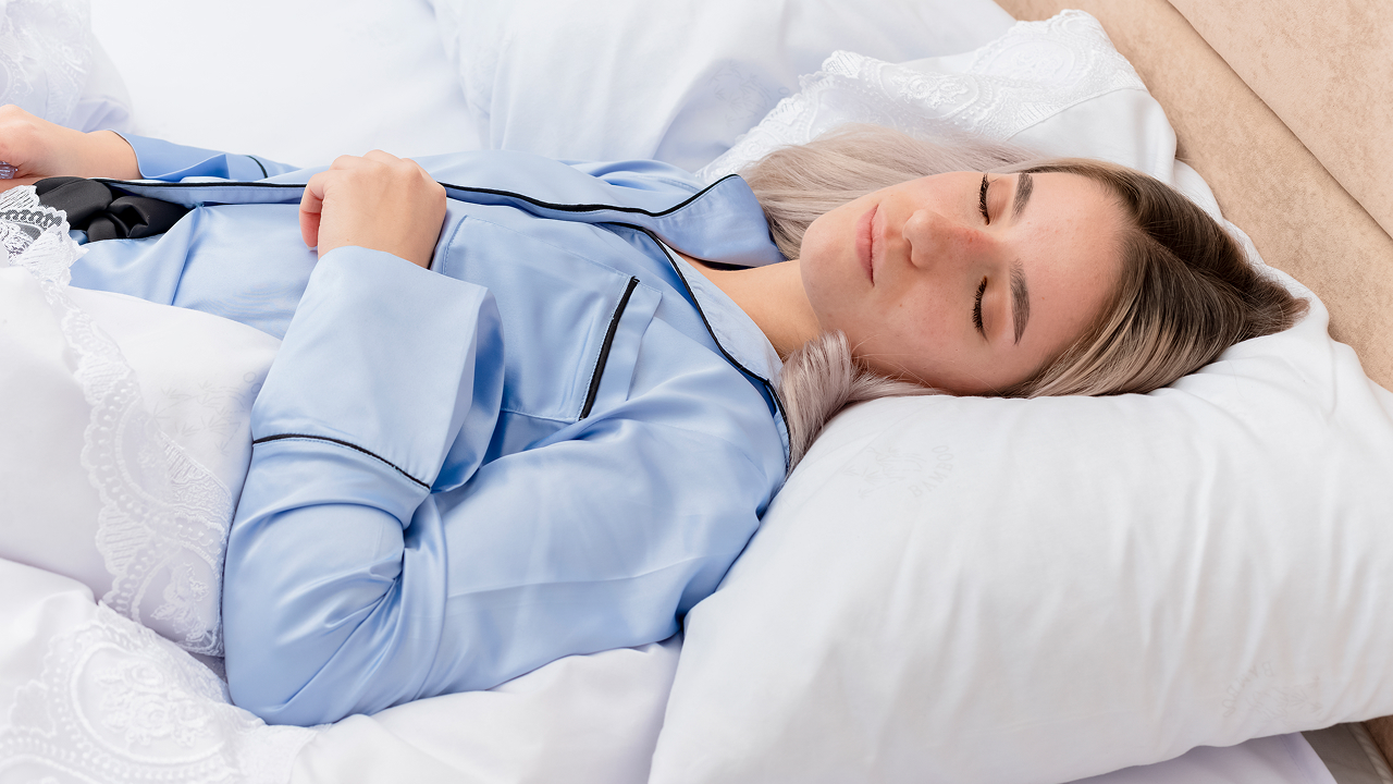 A woman sleeping on a mattress topper, wearing a blue night suit