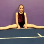 a girl is doing straddle sit which is an acrobatics skill