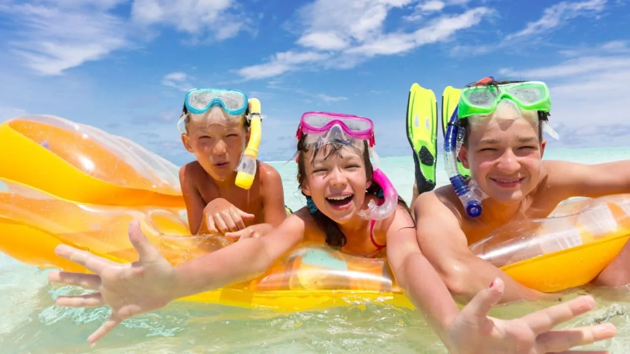 Three children are having fun while swimming on the beach shore