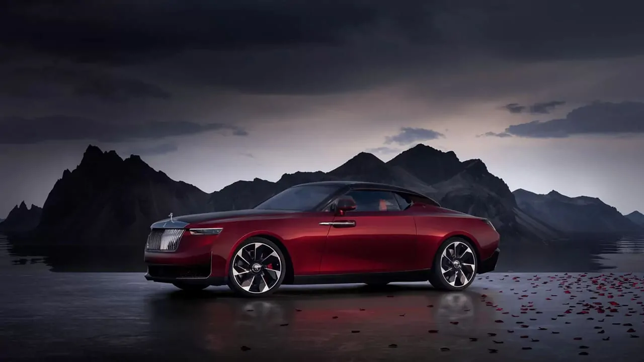 The Rolls-Royce La Rose Noire Droptail is standing in front of a dark, cloudy mountain