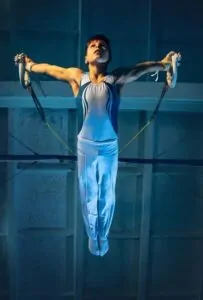 a boy athlete hanging from the ceiling with his arm and core strength