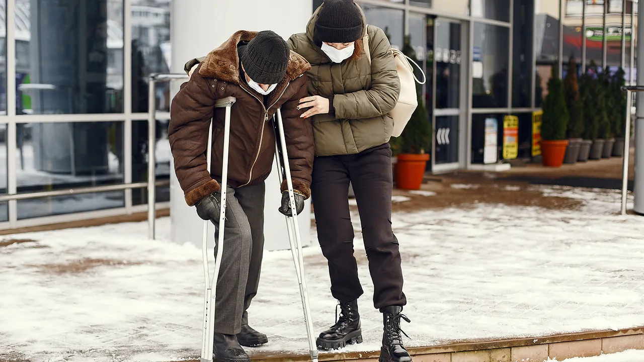 A woman assisting a man who got injured while skiing and snowboarding